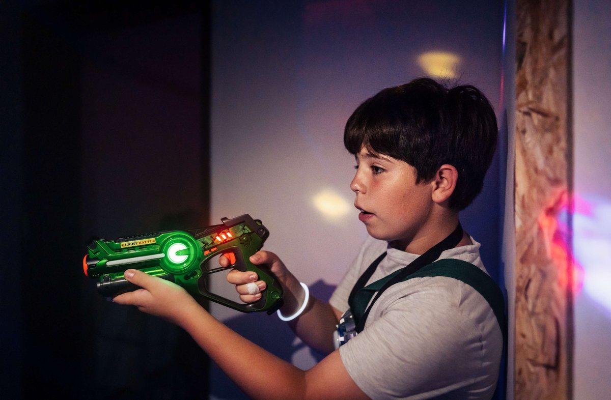 Jongen richt zijn laserpistool in het lasergame-doolhof