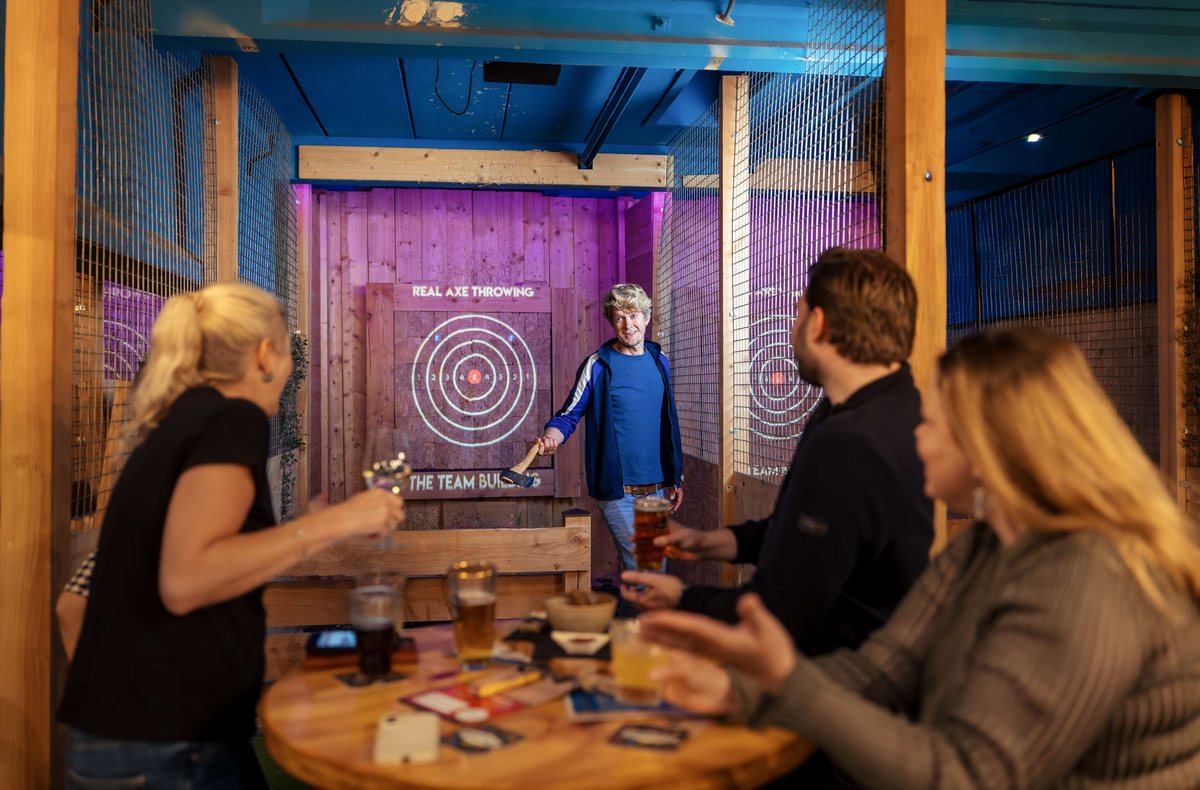 Collega's kijken toe bij een worp op de axe throwing baan in Utrecht