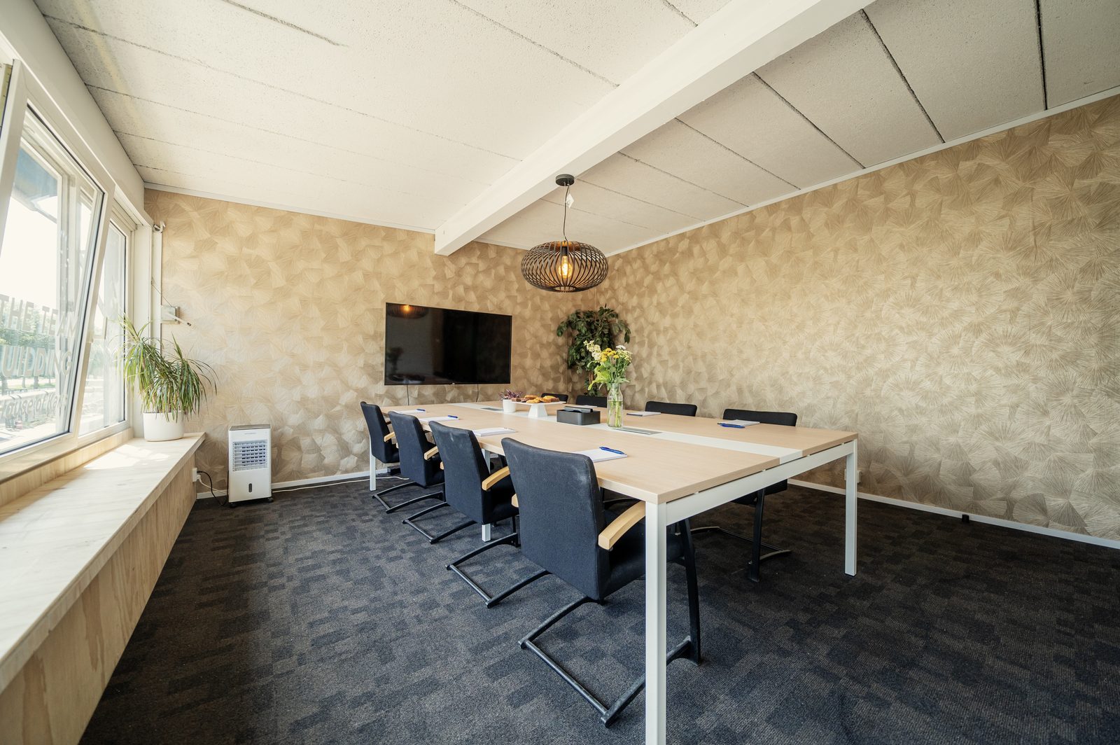 Vergaderzaal in Utrecht met lange tafel, stoelen en een groot scherm